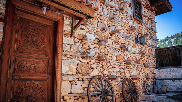 A rustic stone building with a wooden door and two large wheels. - Ayşenaz Hanım Konağı (Akseki)