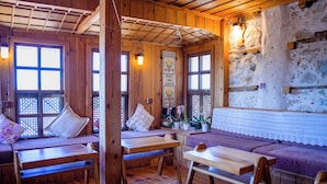 A cozy wooden cabin interior with a bench seating area, a table, and a decorative wall hanging. - Ayşenaz Hanım Konağı (Akseki)