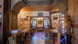 A rustic interior with stone walls, wooden beams, and a central table with chairs. - Ayşenaz Hanım Konağı (Akseki)