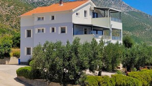 A modern two-story building with a flat roof, multiple windows, and a balcony. - Great 3-Bedroom Apartment with Sea View (Orebic)