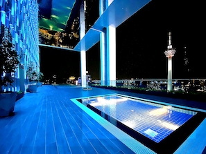 Área de piscina en la azotea con vistas a un horizonte urbano nocturno.