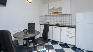 A compact kitchen with white cabinets, a black countertop, and a checkered floor. - Great 2+2 Apartment very close to the sea. (Kuciste)