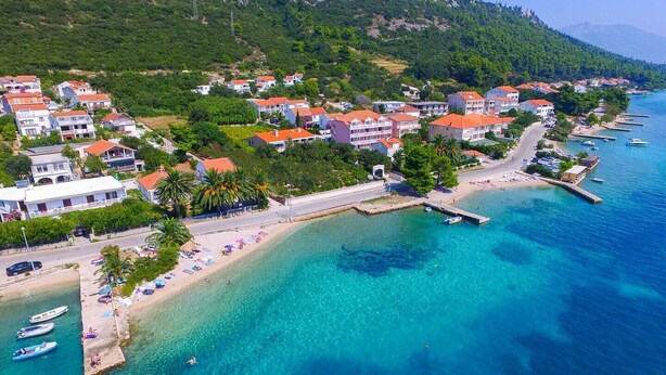 An aerial view of a coastal town with a beach, clear blue waters, and buildings with red roofs. - Great 2+2 Apartment very close to the sea. (Kuciste)