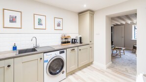 A modern kitchen with a washing machine, a sink, and framed pictures on the wall. - Cosy historic cottage in Hillsborough, near Belfast, Dublin & local attractions (Royal Hillsborough)