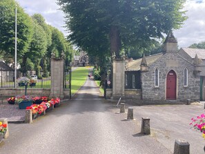 A stone church with a red door, a paved pathway leading to it, and flower beds on either side. - Cosy historic cottage in Hillsborough, near Belfast, Dublin & local attractions (Royal Hillsborough)