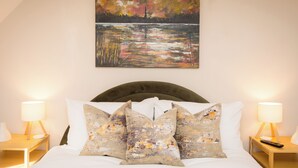 A bedroom with a bed, two bedside tables, a painting, and a lamp. - Cosy historic cottage in Hillsborough, near Belfast, Dublin & local attractions (Royal Hillsborough)