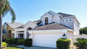 A two-story house with a white garage, a small porch, and a well-maintained lawn. - 🏰 Disney Area 3BR Pool Home | Family-Friendly | Minutes to Golf & Attractions (Davenport)