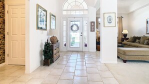 A spacious hallway with a tiled floor, a white door, and a large arched window. - 🏰 Disney Area 3BR Pool Home | Family-Friendly | Minutes to Golf & Attractions (Davenport)