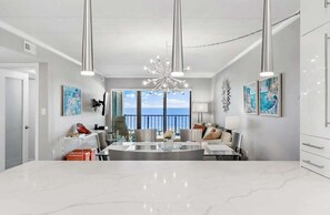 A spacious living room with a large dining table, modern chandelier, and artwork on the walls. - Marigot Beach 310 Oceanfront (Ocean City)