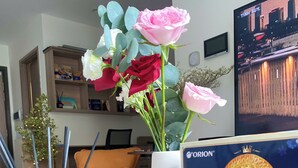 Ett vardagsrum med en soffa, ett soffbord med en vas med blommor, en tv och en bokhylla.
