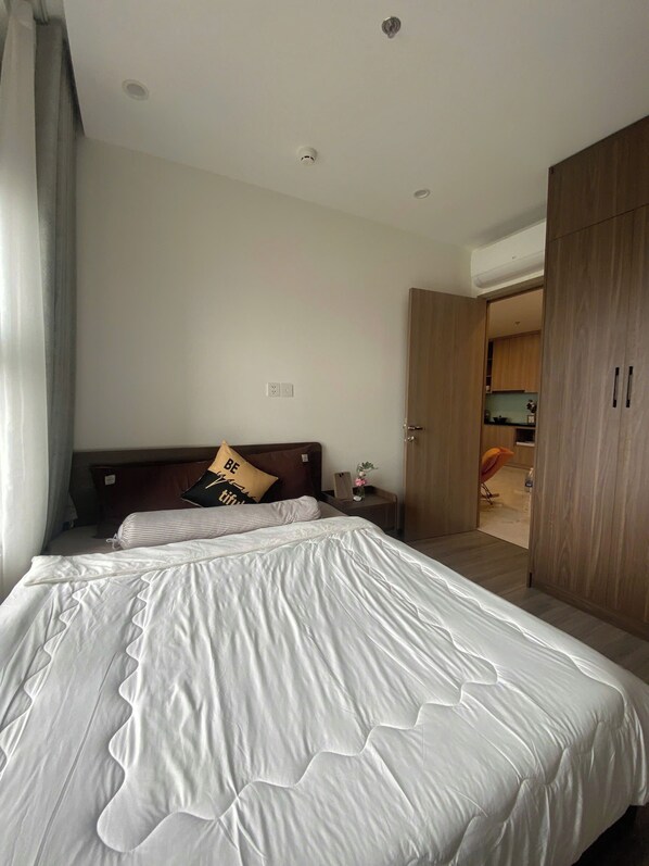 Ein Hotelzimmer mit einem großen Bett, einem Holzschrank und einem kleinen Tisch mit einer Lampe.