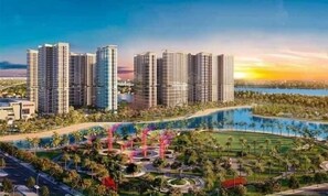 Ein hoher Wohnkomplex mit mehreren Gebäuden, einem angelegten Park mit Palmen und einem Wasserlauf.