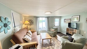 Una sala de estar con sofá, sillón, mesa de centro y mueble para televisión.