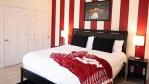 A hotel room with a bed, a nightstand, a wall-mounted TV, and a door. - Hoosier Suite Modern Studio Downtown on the Square (Bloomington)