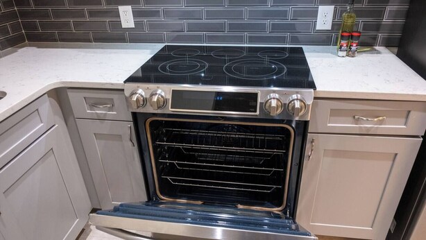 A kitchen with a built-in oven and stovetop, a white countertop, and a backsplash. - Hoosier Suite Modern Studio Downtown on the Square (Bloomington)