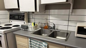 A kitchen with white cabinets, a double sink, a stove, and a toaster. - Maryland Homestay - Downtown Apartment #1 (Winnipeg)