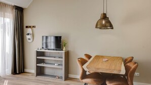 Ein modernes Wohnzimmer mit einem Holzesstisch, Ledersesseln, einer grauen Unterhaltungsecke und einer hängenden Pendelleuchte.