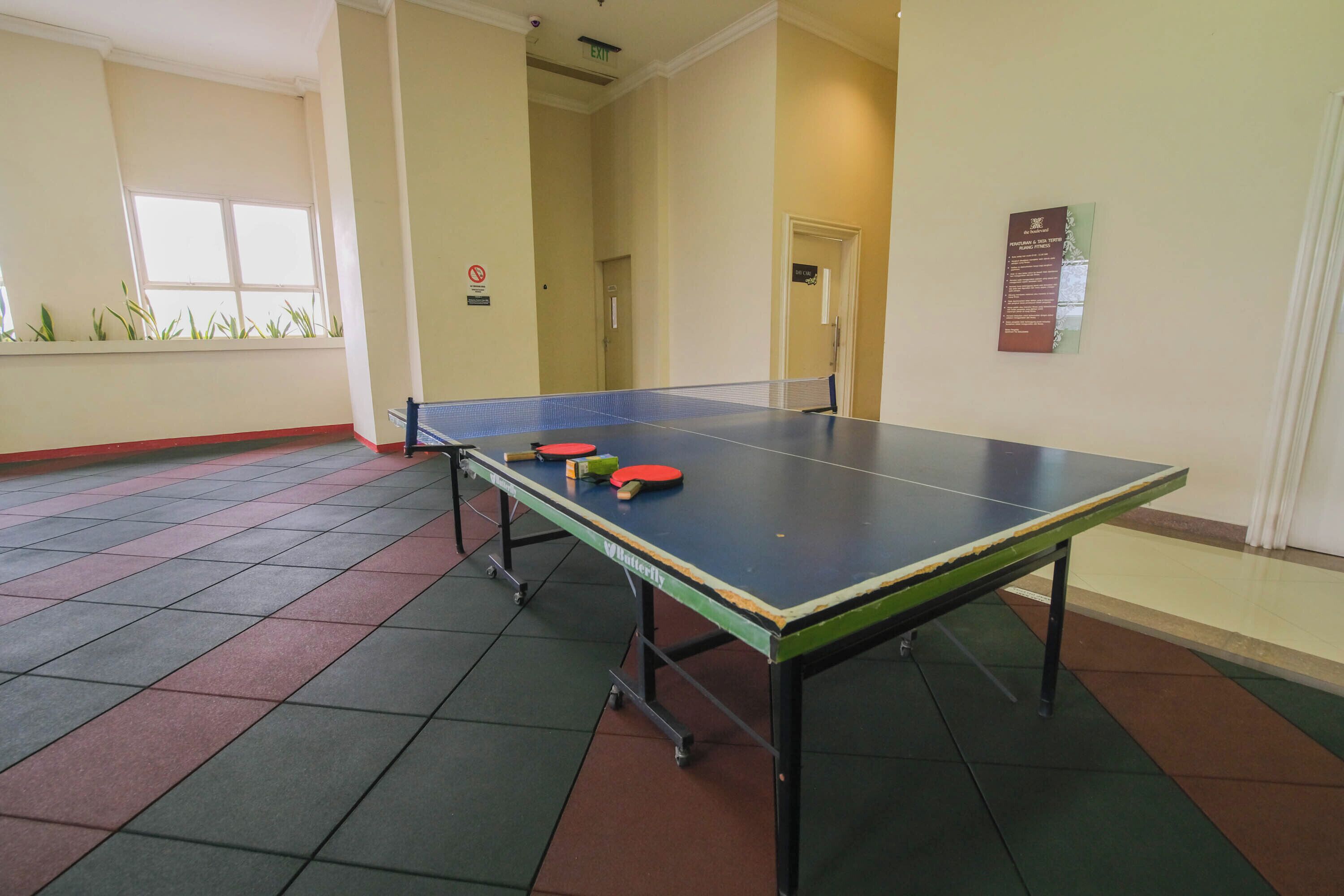 Ein Tischtennistisch in einem Raum mit Fliesenboden und einer Tür im Hintergrund.