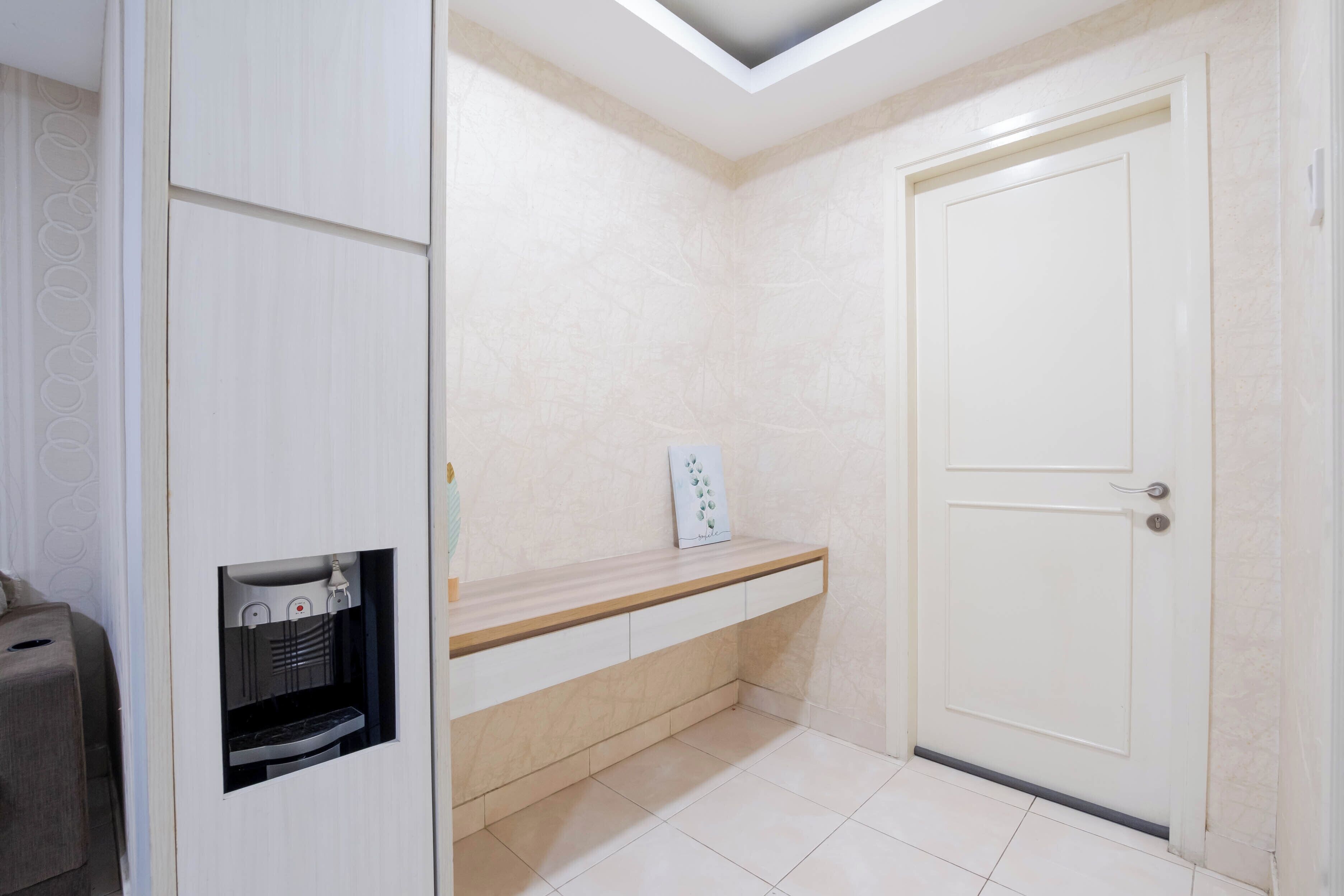 A room with a white door, a built-in bench, and a small shelf with a decorative item.