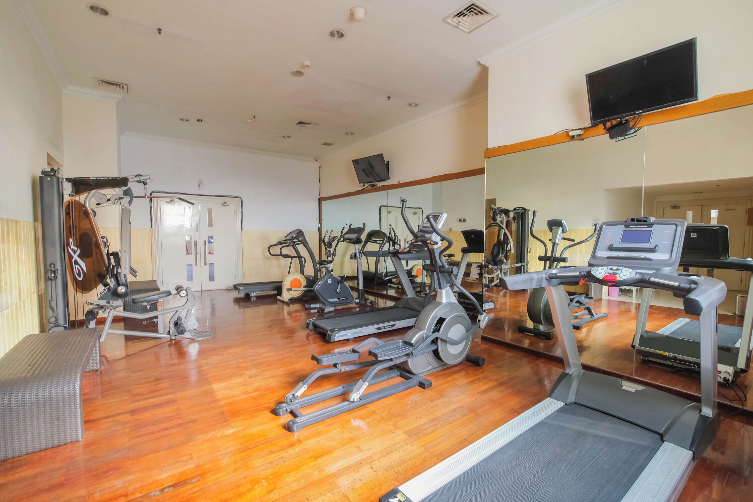 Une salle de sport équipée de tapis de course, de vélos elliptiques et d’un vélo d’appartement.