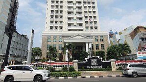 A tall, multi-story hotel with a prominent entrance and a sign reading "The Boulevard." - The Boulevard Apartment By Abdihome (Jakarta)