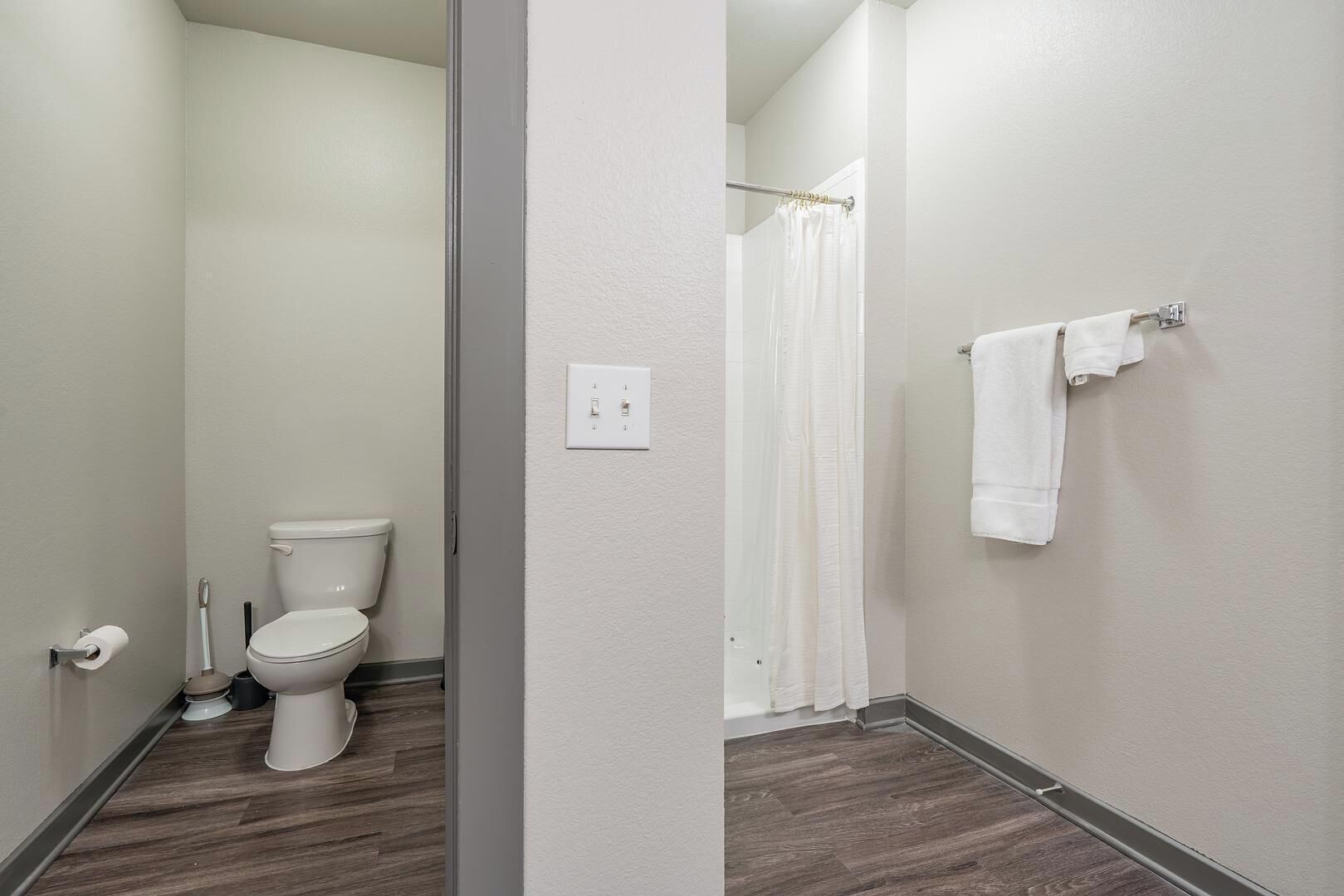 A bathroom with a toilet, a shower curtain, and a towel rack.