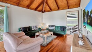 A spacious living room with a high wooden ceiling, a green sofa, a beige armchair, and a coffee table. - Sundowner is the perfect escape for a relaxing holiday (Point Lookout)