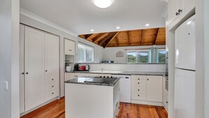 A kitchen with white cabinets, a central island with a stove, and wooden flooring. - Sundowner is the perfect escape for a relaxing holiday (Point Lookout)