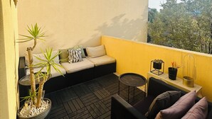 A balcony with a sofa, a small table, and potted plants.