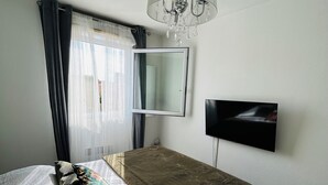 A bedroom with a bed, a mirror, a TV, and a chandelier.