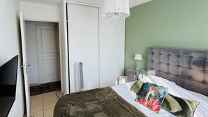 A bedroom with a bed, a chandelier, a wardrobe, and a television.
