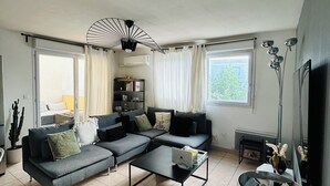 A modern living room with a sectional sofa, a coffee table, and a unique ceiling fan.