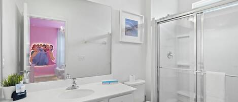 Casa de banho moderna com um espelho grande, lavatório branco e cabine de duche em vidro.