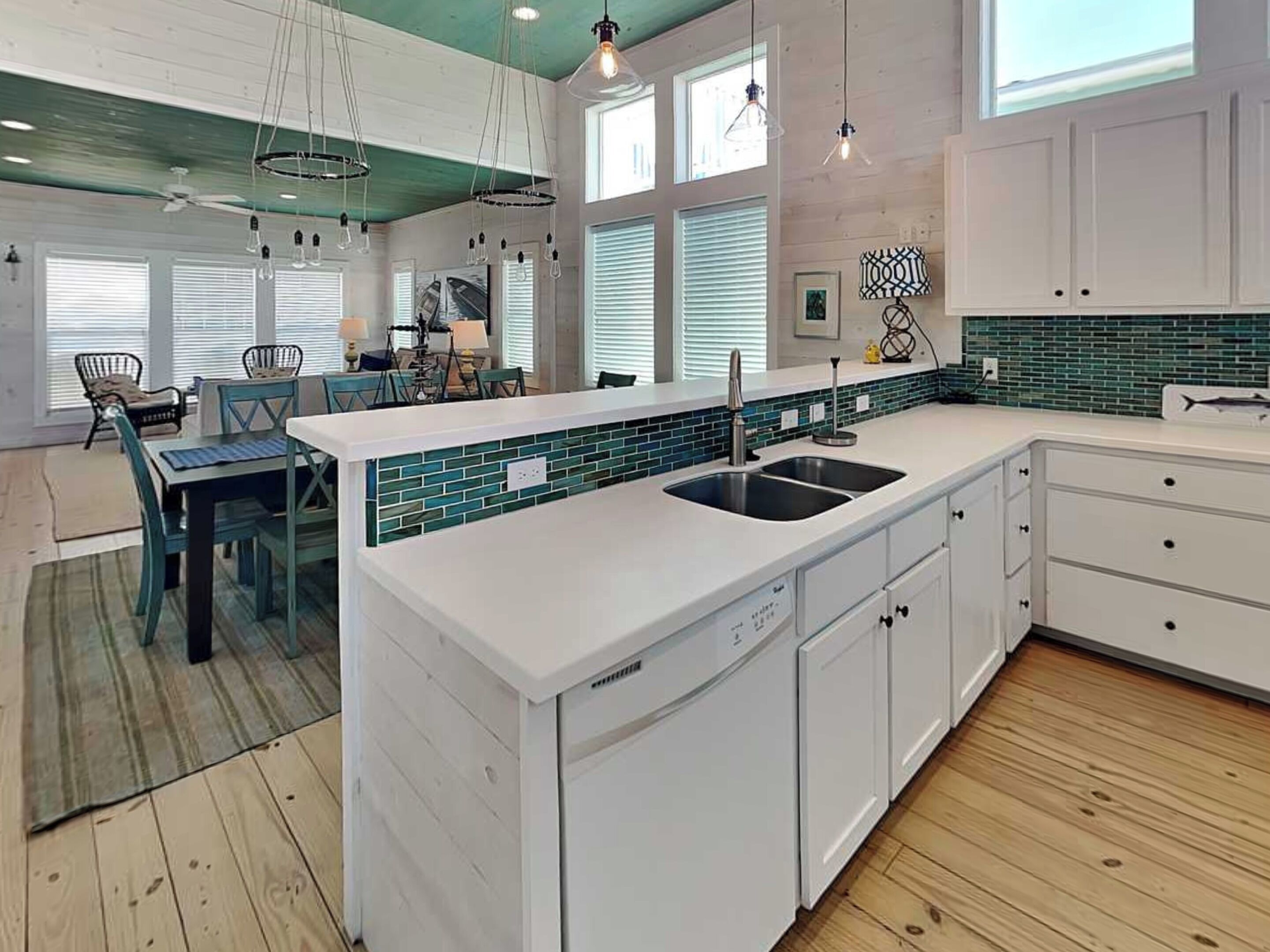 Una cocina moderna con una isla blanca, un lavamanos doble y un salpicadero azul turquesa.
