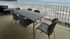 Un balcón con mesa y sillas con vista a la playa.
