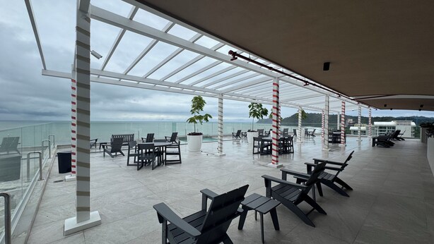 Una terraza al aire libre con mobiliario, piscina y vistas al mar.