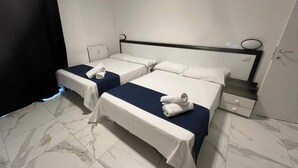 Hotellihuone, jossa on kaksi erillistä sänkyä, yöpöytä, lipasto ja kylpyhuoneen ovi.