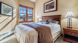 A bedroom with a large bed, a nightstand, a lamp, and two framed pictures on the wall. - Entire condo in Avon, Colorado (Avon)