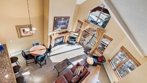 A spacious living area with a fireplace, a dining table with chairs, a sofa, and a large window offering a view of the outdoors. - Entire condo in Avon, Colorado (Avon)