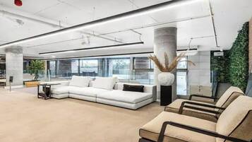 A modern lobby with a white sofa, beige chairs, and a large window.