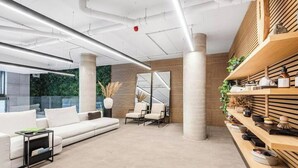 A modern interior with a white sofa, a small table, and a wooden shelf with decorative items. - Stunning Flat swimming pool/gym (London)