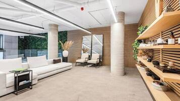 A modern interior with a white sofa, a small table, and a wooden shelf with decorative items.