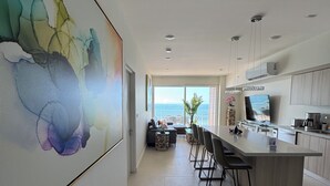 Eine moderne Küche mit einer großen Kochinsel, Barhocker und Meerblick.