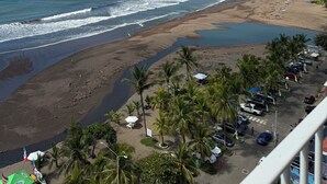 Ein Strand mit Palmen, einem Parkplatz und Blick aufs Meer.