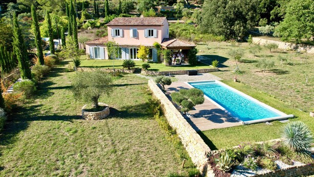Ein zweigeschossiges Haus mit Swimmingpool, umgeben von einem gepflegten Rasen und Garten.