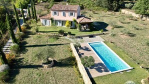 Ein zweistöckiges Haus mit Swimmingpool, umgeben von einem gepflegten Rasen und Bäumen.