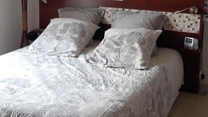Ein Schlafzimmer mit einem Bett, einem Nachttisch, einer Lampe und einer Wanddekoration.