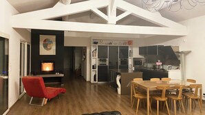 A modern living room with a fireplace, a dining area with wooden furniture, and a kitchen with dark cabinets. - Private pool villa in listed village, St Remy de Provence, les Alpilles.  (Saint-Rémy-de-Provence)