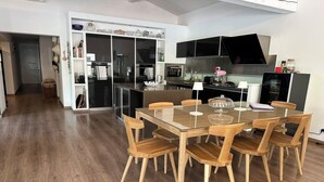 A modern kitchen with a dining area, featuring a glass-top table and wooden chairs. - Private pool villa in listed village, St Remy de Provence, les Alpilles.  (Saint-Rémy-de-Provence)