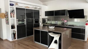 A modern kitchen with black cabinets, a central island, and a built-in oven. - Private pool villa in listed village, St Remy de Provence, les Alpilles.  (Saint-Rémy-de-Provence)
